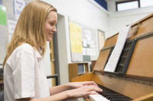 Schoolgirl playing piano in music class